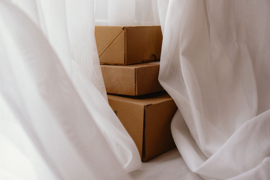 A close-up view of three neatly stacked cardboard boxes, likely containing floral arrangements or flowers, partially enveloped by white tissue paper, suggesting packaging for flower delivery from flor